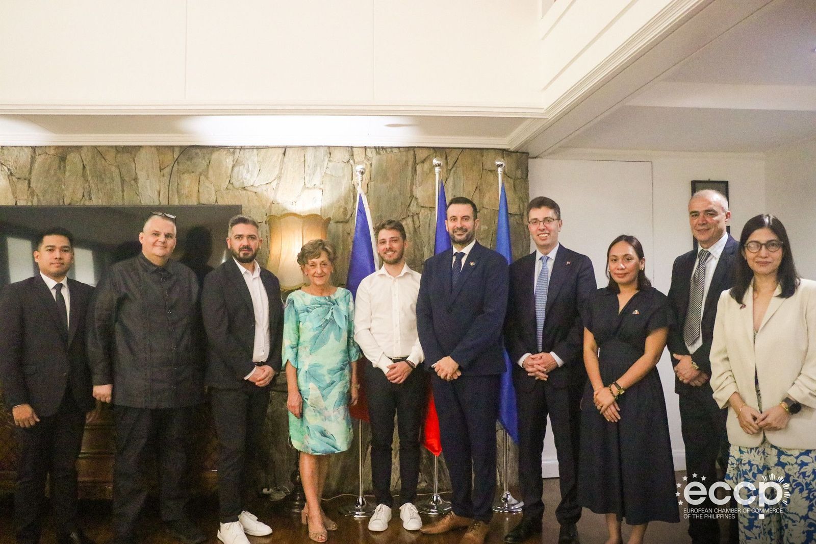 Alin Roșca standing with ten guests in front of a stone wall and flags at the partnership signing