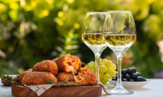 Olives noires, suppli et verre de vin blanc