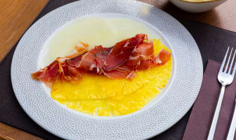 Une assiette de carpaccio d'ananas et de melon avec des fines lamelles de jambon