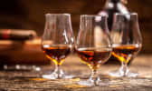 3 verres de rhum brun sur table en boie