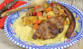 Belle assiette de couscous avec semoule, légumes, agneau et merguez