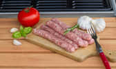 Chipolata sur planche de bois, ail, tomate et basilic
