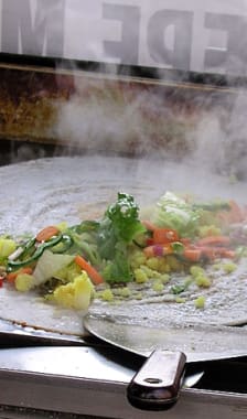 Cuisson d'un dosa garni de salade et légumes divers