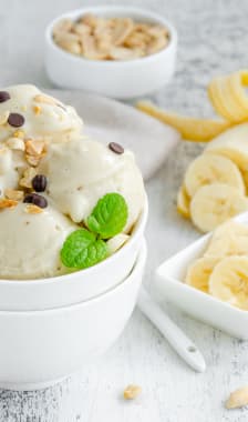 Glace à la banane vegan faite maison dans un bol avec cacahuètes et chocolat