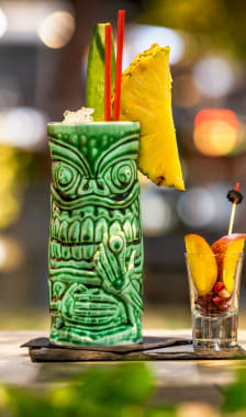 Verre de cocktail tiki posé sur un bar avec des fruits