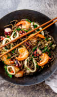 Nouilles sautées aux fruits de mer dans un wok asiatique en fonte