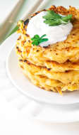 Pile de galettes de pommes de terre sur une assiette blanche, avec de la crème