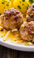 Boulettes de porc poêlées avec oignon frit, pommes de terre bouillies et laitue à la crème sur table en bois