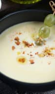 Ajoblanco dans un bol noir et brochette de raisin