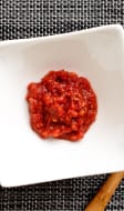 Gochujang sur fond tissé et cuiller en bois
