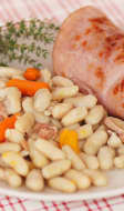 Tranche de jambon grillé et haricots blancs mogettes de Vendée dans une assiette blanche