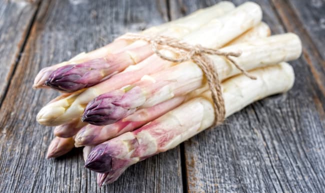 Botte d'asperges violette sur fond bois