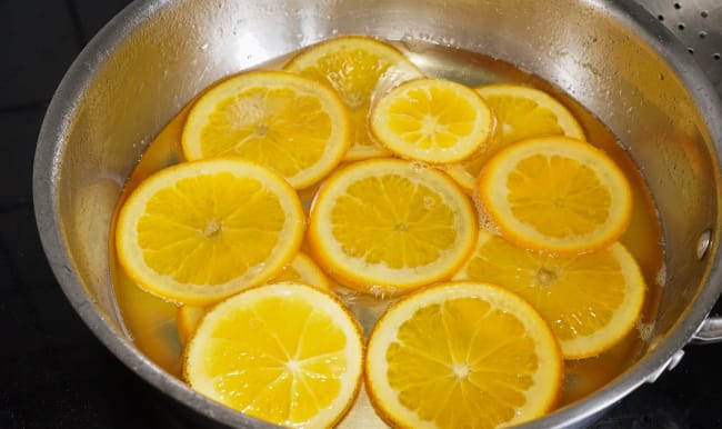 Tranches d'orange en train de confire dans le sirop