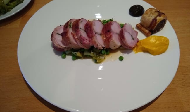 Râble de lapin farci, saucisse, petits pois, crème de carottes et purée de noix marinées