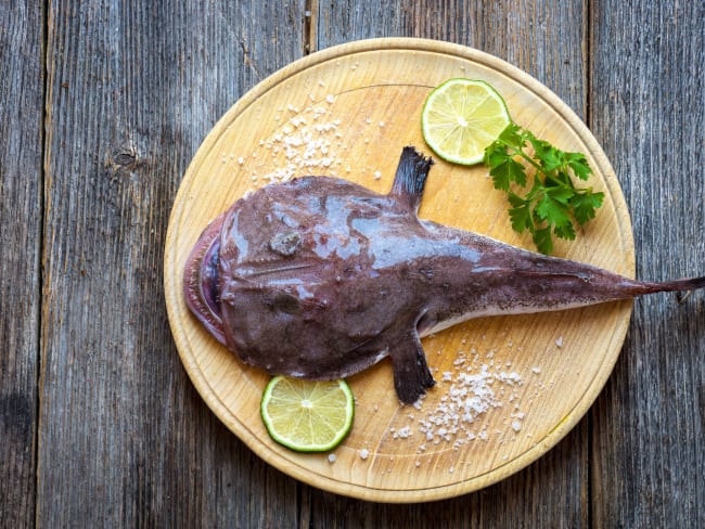 Lotte entière sur une plat en bois avec des rondelles de citron