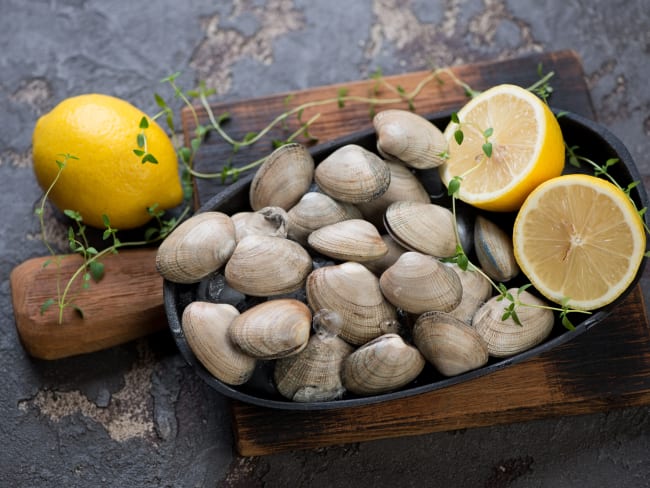 Petit plateau de palourdes sur planche de bois et citrons