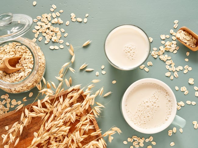 Verre et mug de lait d'avoine, épis et flocons