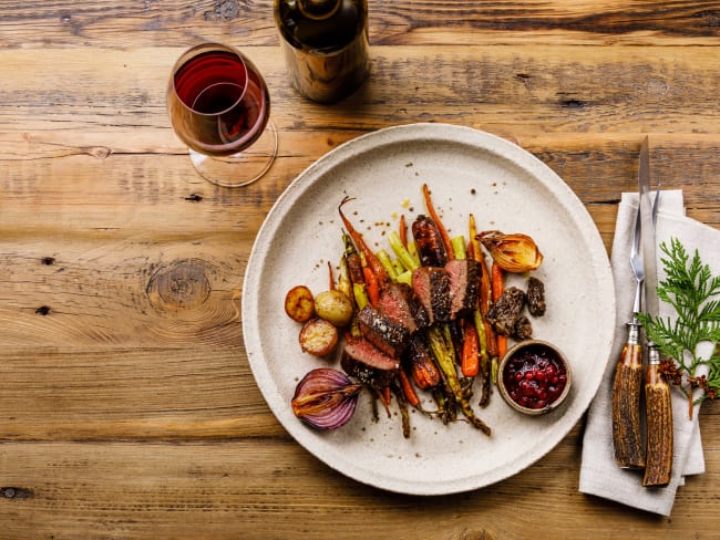 Tranches de steak de gibier grillées avec légumes cuits au four et sauce aux baies et vin rouge