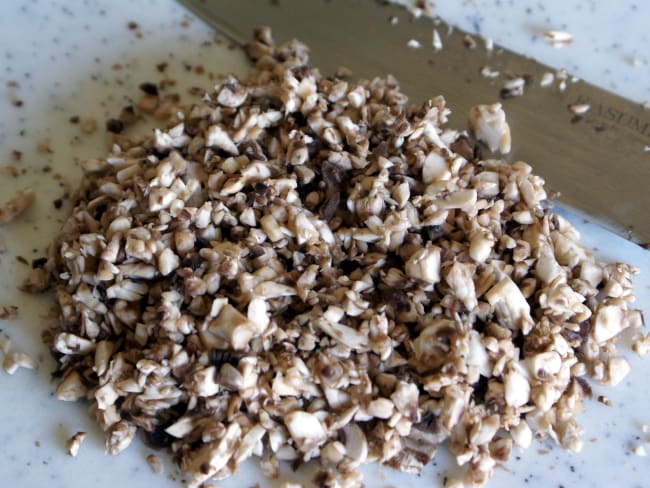 Champignons de Paris taillés en duxelles sur planche.