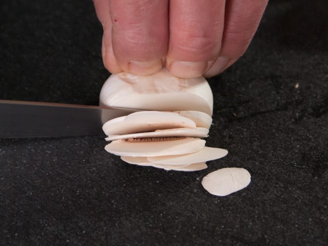 Champignons émincés sur planche noire.