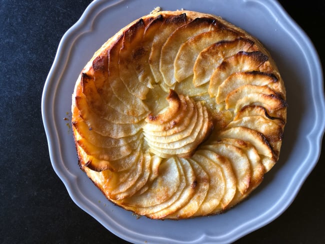 Tarte aux pommes sur assiette grise et fond noir