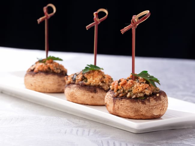 Champignons farcis sur assiette posée sur nappe blanche