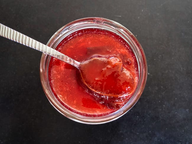 Cuillère dans un bocal de confiture de prunes rouges