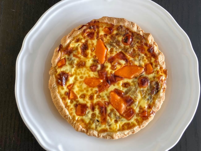 Quiche endives mimolette dans une assiette blanche sur fond noir