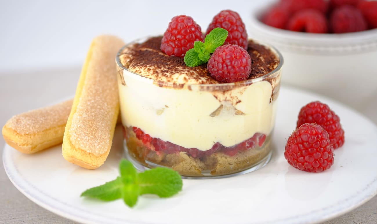 Tiramisu aux framboises en verrine sur assiette blanche