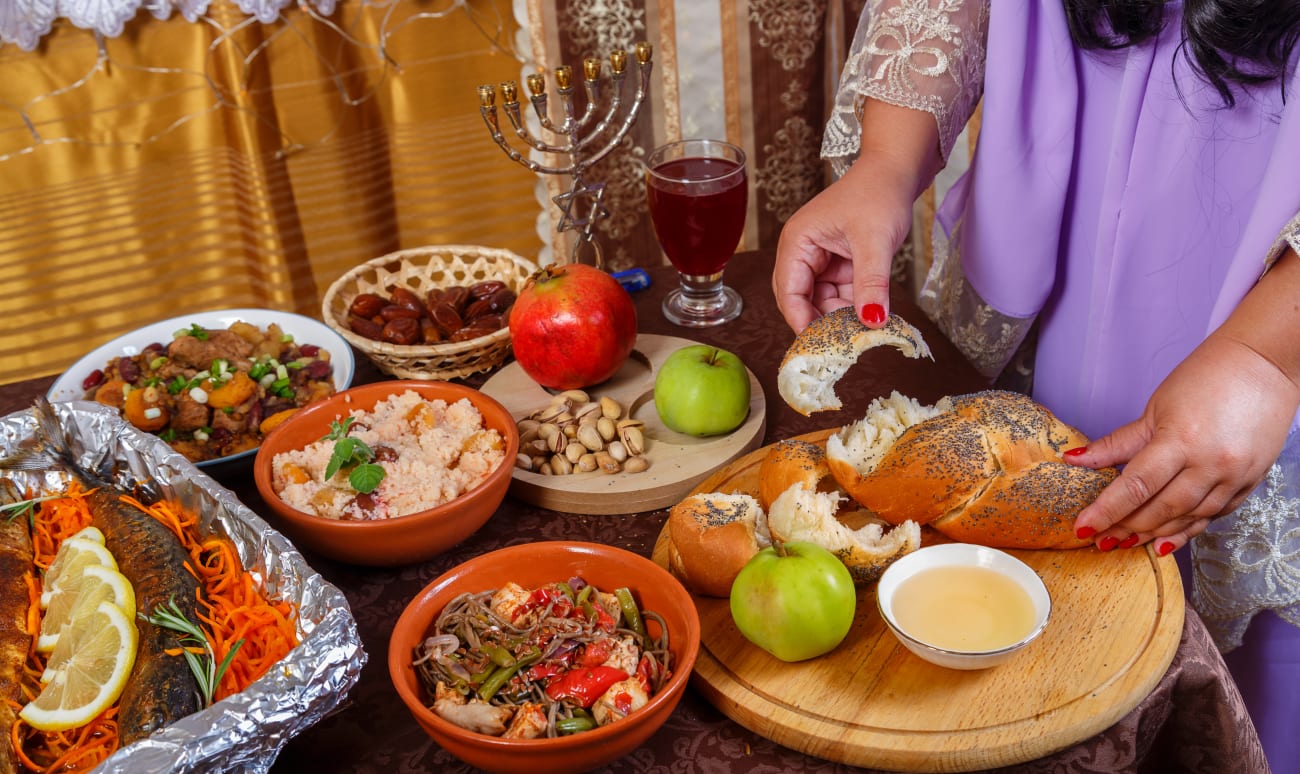 Une femme rompt la challah sur la table dressée lors de la fête juive de Rosh Hachana.