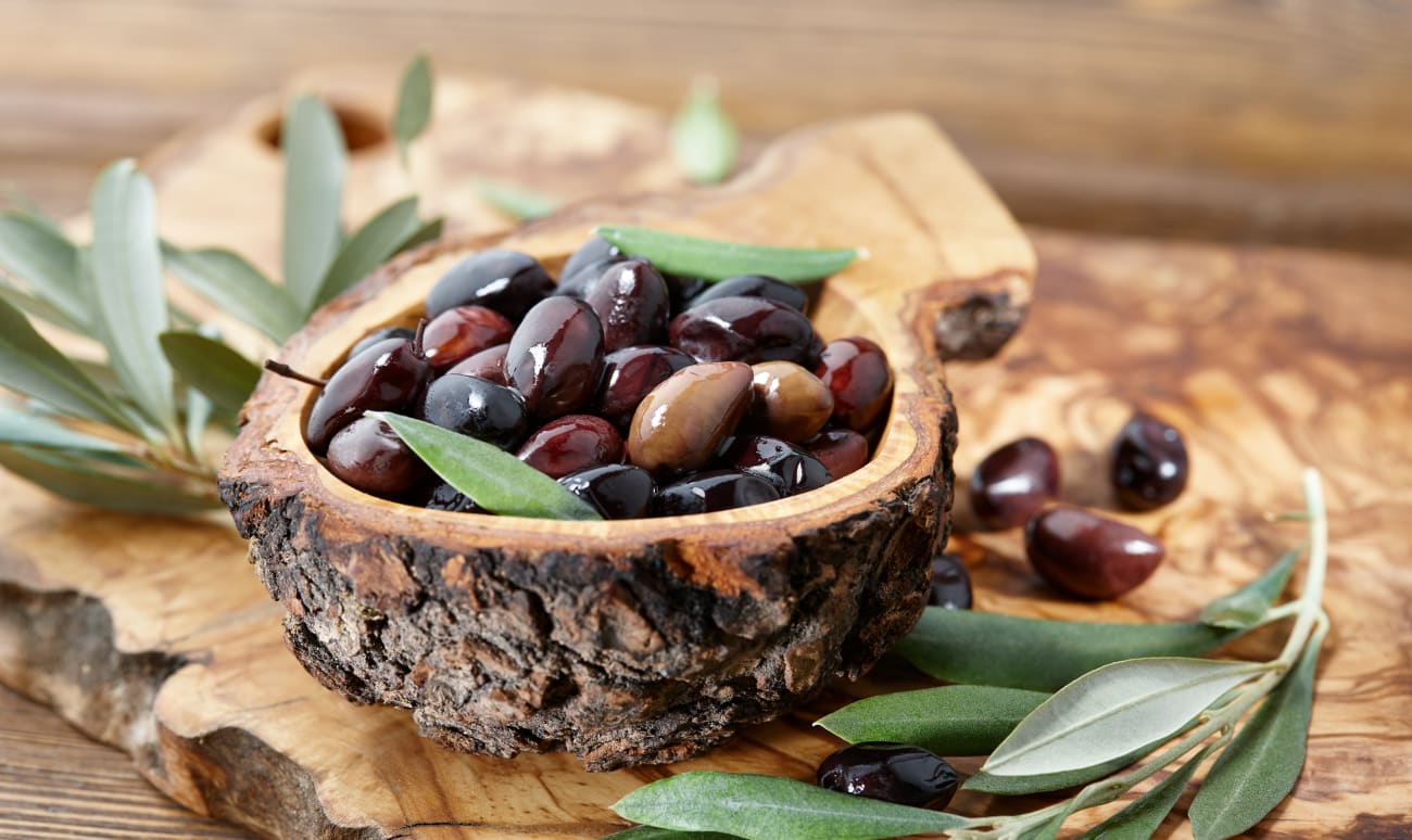 Olives de Kalamata et feuilles d'olivier dans un bol en bois