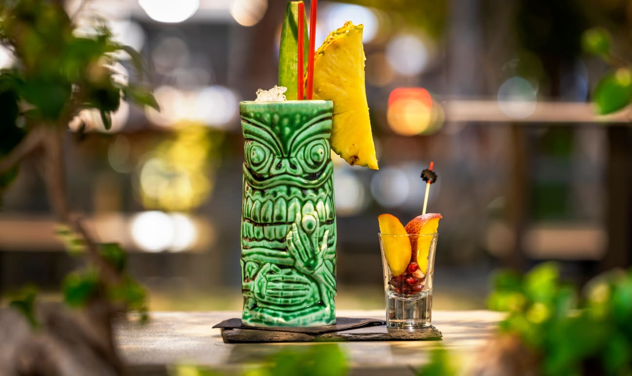 Verre de cocktail tiki posé sur un bar avec des fruits