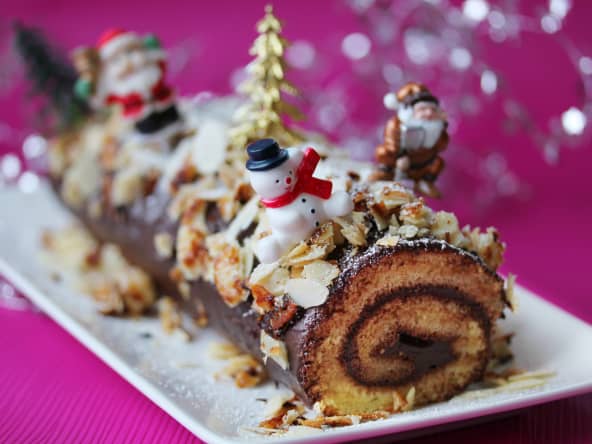 Bûche de noël roulée décorée avec sapins et bonhommes de neige