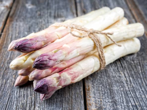 Botte d'asperges violette sur fond bois