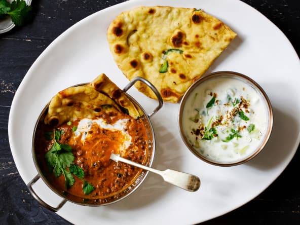 Curry, naan et raïta sur plat blanc