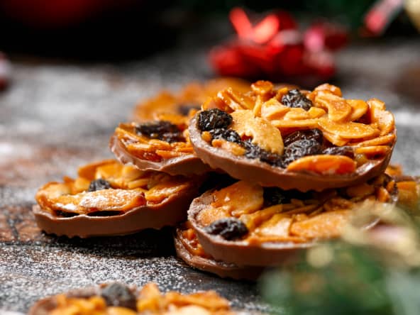 Biscuits florentins au chocolat de Noël aux amandes et aux raisins secs, décorés, cadeaux, branche de sapin verte sur une table rustique en bois