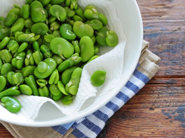 Fèves cuites et écossées sur assiette blanche