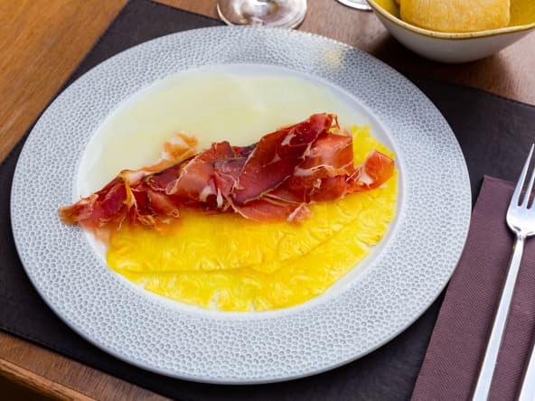 Une assiette de carpaccio d'ananas et de melon avec des fines lamelles de jambon