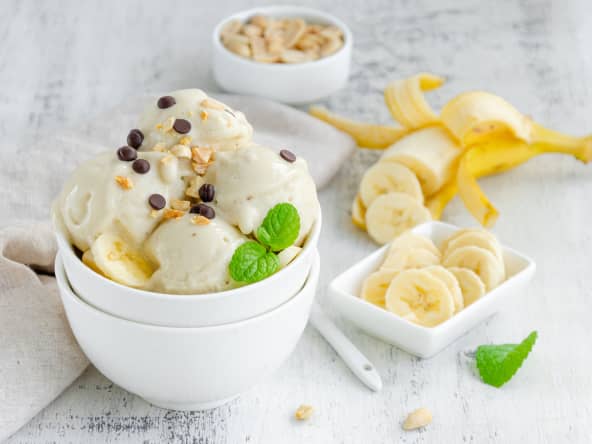 Glace à la banane vegan faite maison dans un bol avec cacahuètes et chocolat