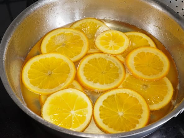 Tranches d'orange en train de confire dans le sirop