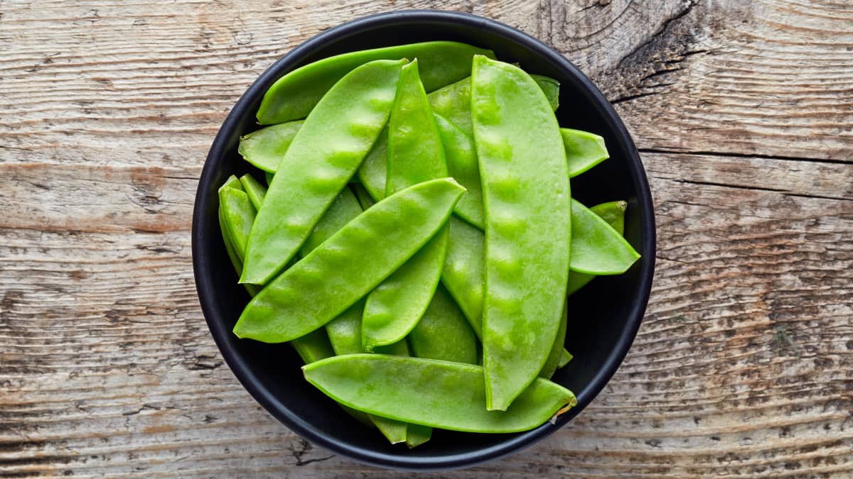 Bol de pois gourmands sur table en bois
