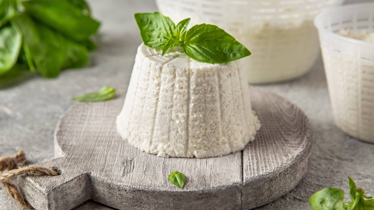Ricotta maison posée sur planche et basilic