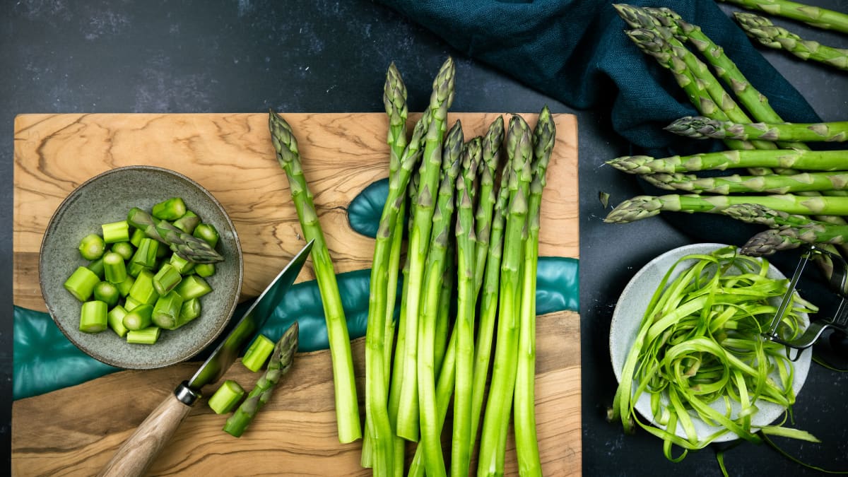 Asperges vertes épluchées sur une planche en bois