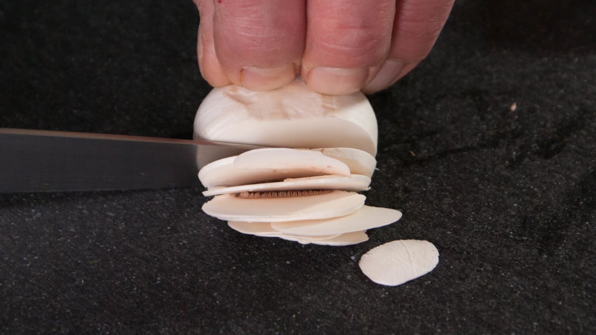 Champignons émincés sur planche noire.