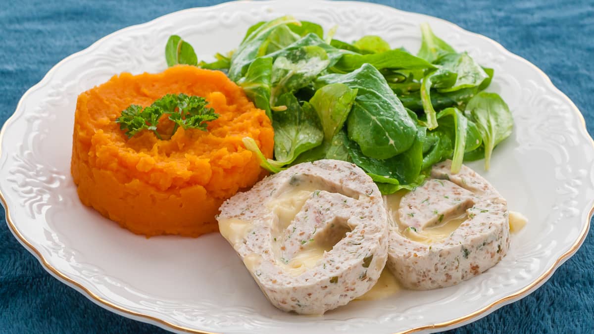 Assiette de roulé de volaille, sauce au chorizo servi avec une salade verte et une purée