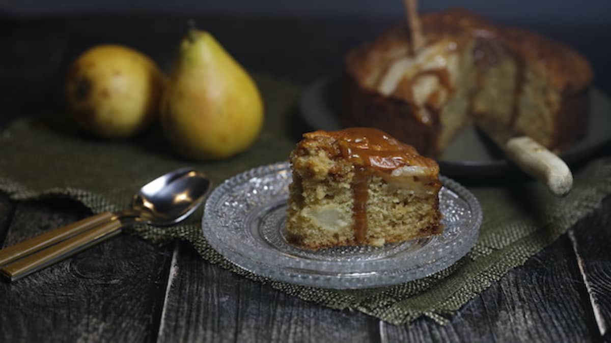 Belle part de gâteau aux poires fromage blanc et caramel salé dans une assiette en verre