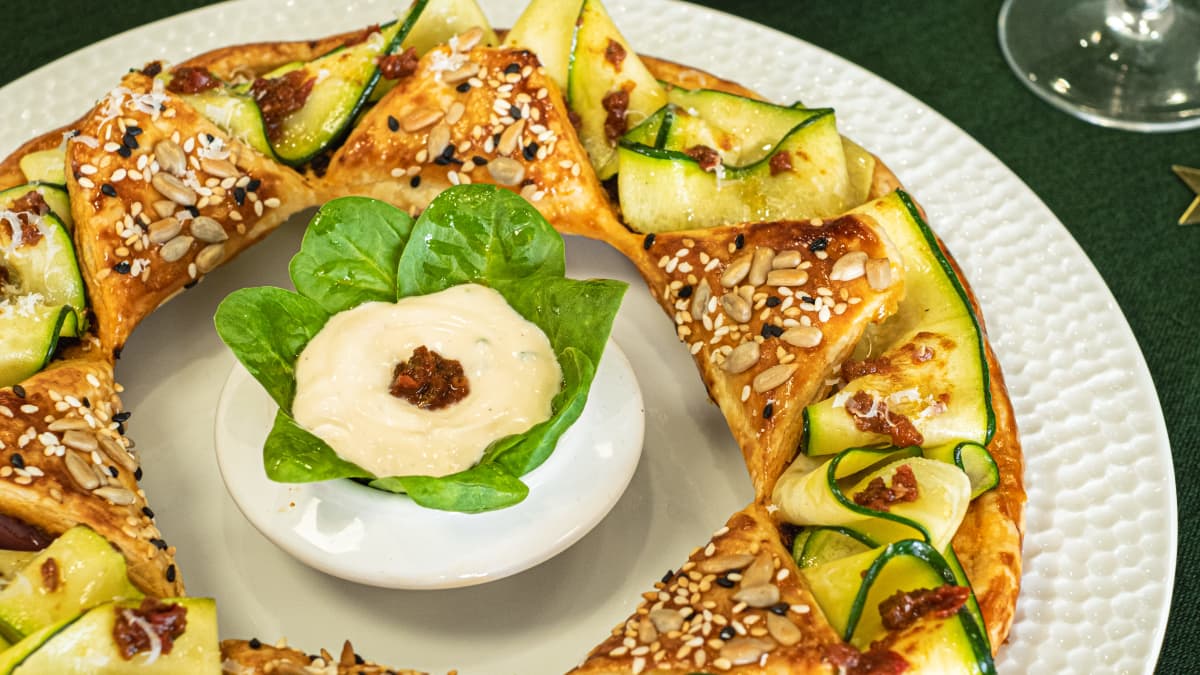 Couronne feuilletée aux courgettes marinées sur une assiette blanche avec petit bol de dip