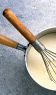 Sauce béchamel en préparation dans une casserole, avec un fouet