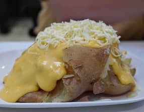 Pommes de terre farcies aux oeufs, en sauce au fromage, gratinées au four