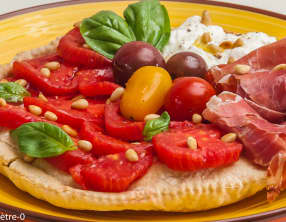 Pizza à la garniture crue de jambon, tomates et burrata